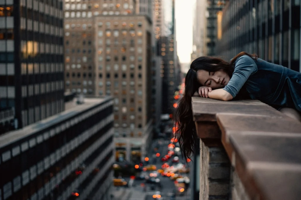 Woman experiencing burnout on a building ledge.